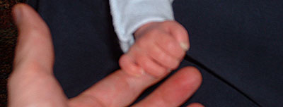 small hand grasping an adult finger